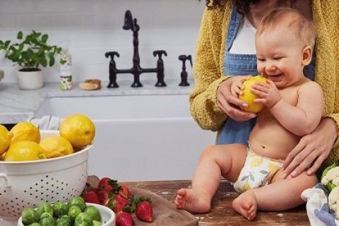 Ein Baby interessiert sich für eine Zitrone.