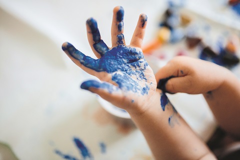 Ein Kind experimentiert mit blauer Fingerfarbe
